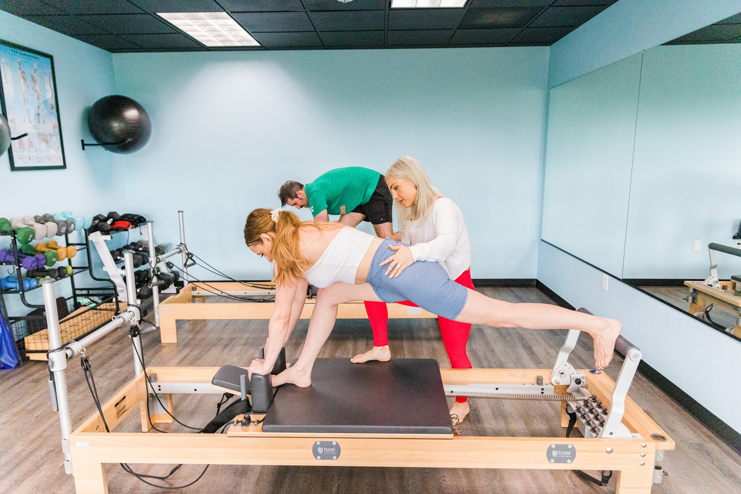Pilates instructor leading students on Pilates reformers