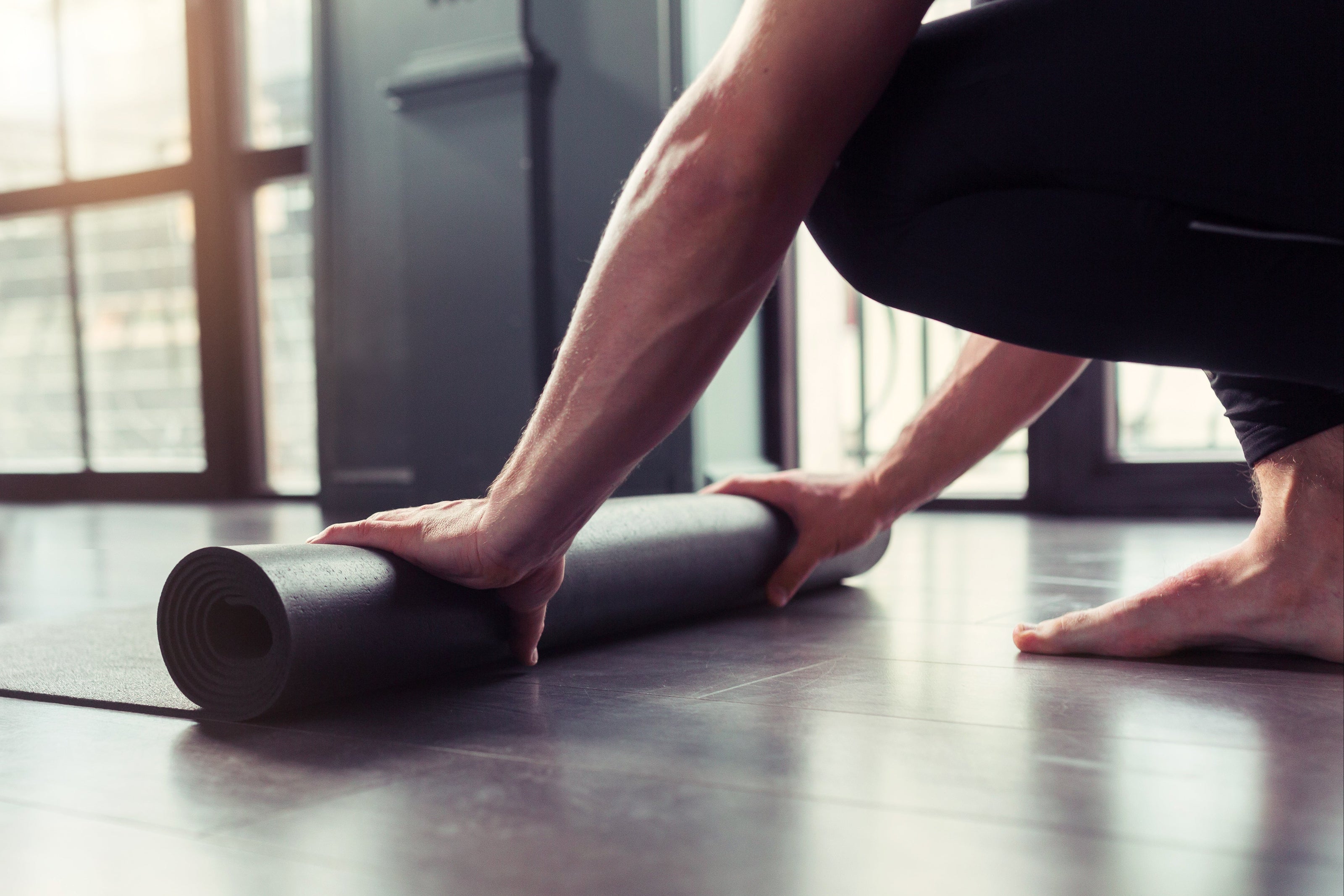 man rolling out yoga mat