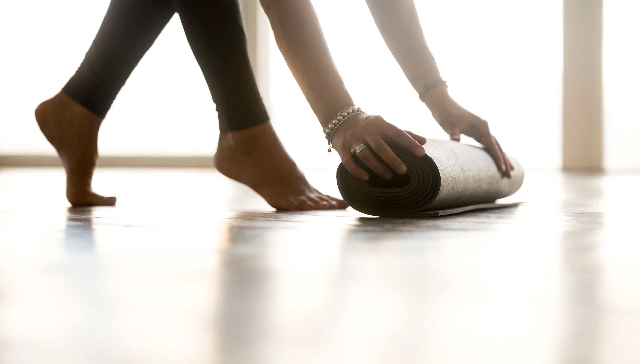 woman with rolled pilates mat